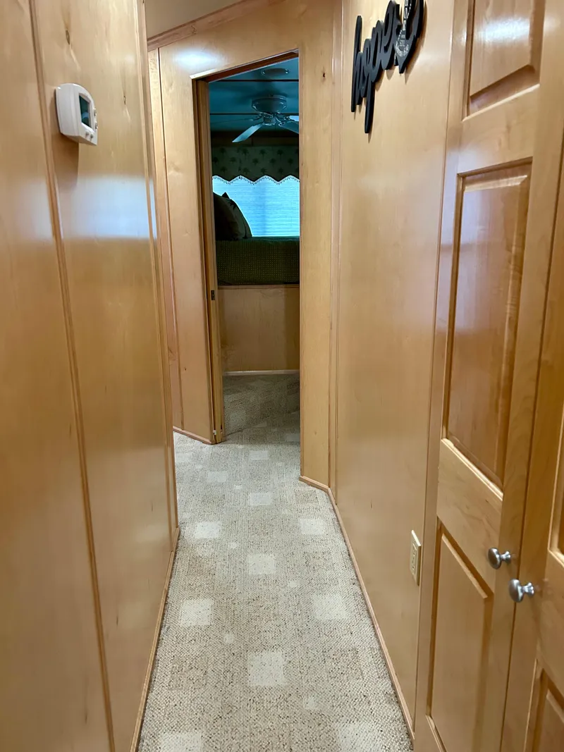 Slide: The Image of Narrow hallway inside a 2004 Horizon houseboat with wooden walls and carpet flooring. - 15