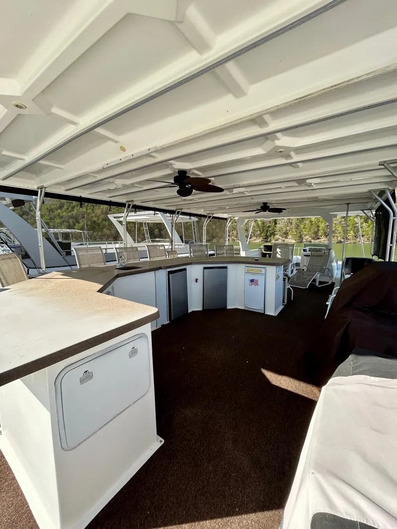 Slide: The Image of 2004 Horizon houseboat interior with spacious deck, bar area, and ceiling fans. - 24