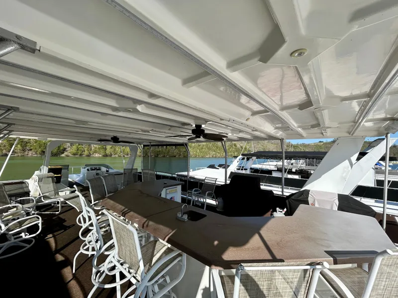 Slide: The Image of 2004 Horizon houseboat deck with seating, bar area, and scenic lake view. - 26