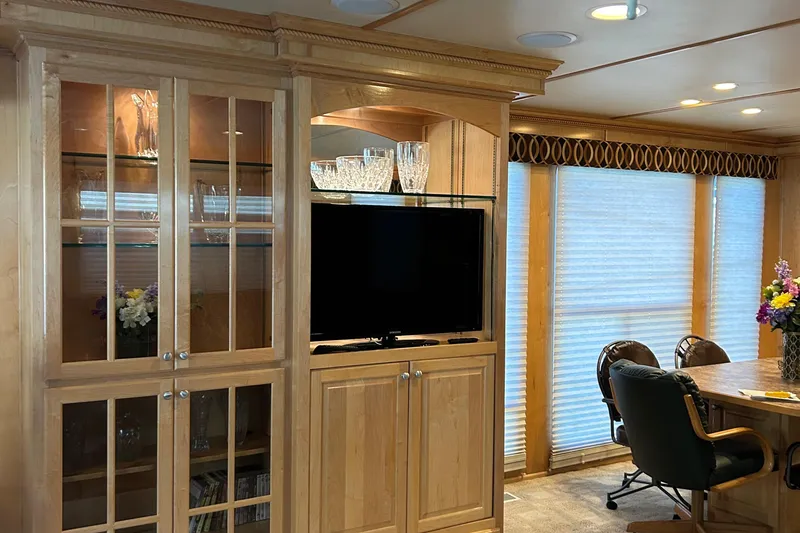 Slide: The Image of Interior of a 2004 Horizon houseboat featuring wooden cabinetry, a TV, and dining area. - 6
