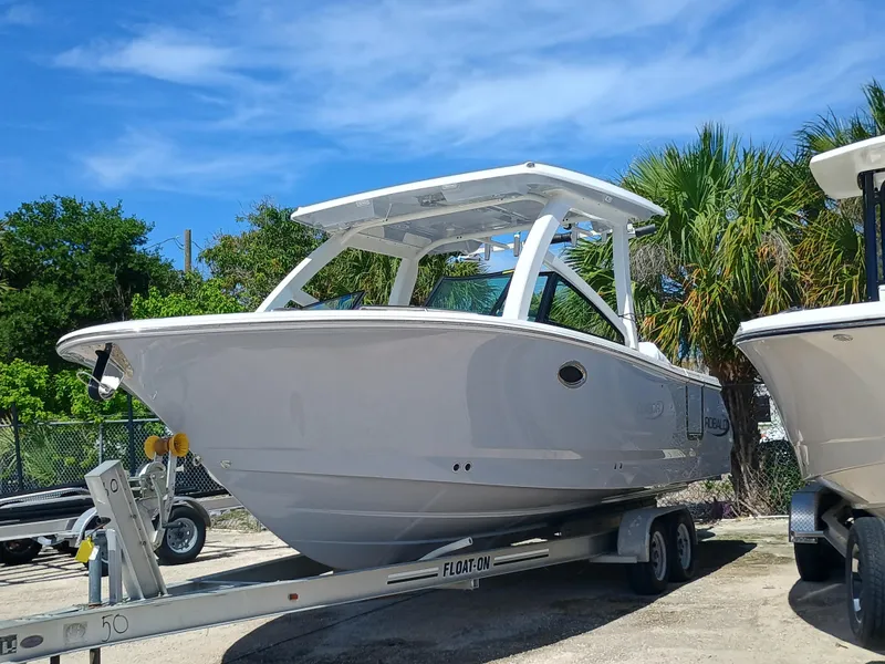 The Image of 2025 Robalo R257 Dual Console boat on trailer, surrounded by palm trees. - 1