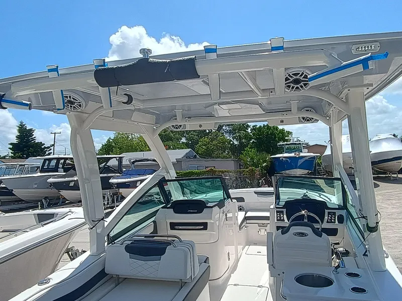 Slide: The Image of 2025 Robalo R257 Dual Console boat interior with seating and helm, under a clear blue sky. - 13