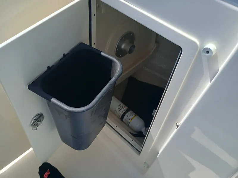 Slide: The Image of 2025 Robalo R257 Dual Console storage compartment with trash bin and fire extinguisher. - 24