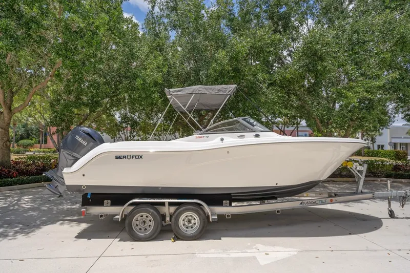 Slide: The Image of 2025 Sea Fox 228 Traveler boat on trailer, parked outdoors under trees. - 6