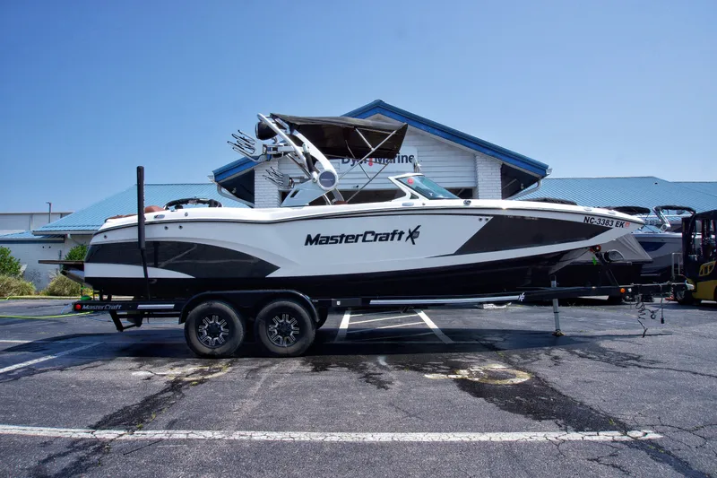 The Image of 2018 MasterCraft X46 boat on trailer, parked outside a building under clear blue sky. - 1
