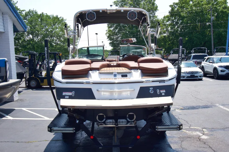 Slide: The Image of 2018 MasterCraft X46 boat, rear view, parked in a lot with cars and trees. - 7