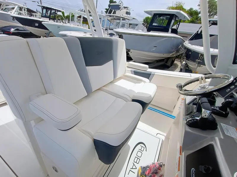 Slide: The Image of 2025 Robalo R270 Center Console boat interior with white and gray seating, steering wheel, and controls. - 18
