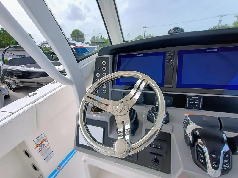 Slide: The Image of 2025 Robalo R270 Center Console helm with dual Simrad displays and sleek steering wheel. - 24
