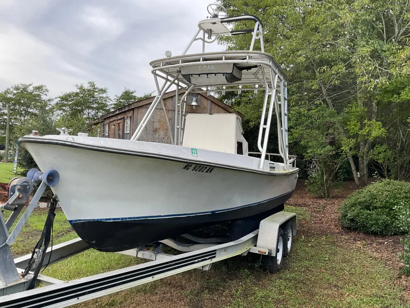 Slide: The Image of 1978 Shamrock 200 cc boat on trailer, parked outdoors near trees and a wooden building. - 5