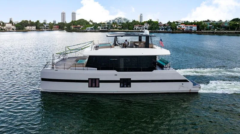Slide: The Image of 2018 Sunreef 70 yacht cruising on a scenic waterway with city skyline backdrop. - 14