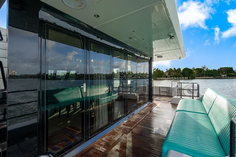 Slide: The Image of Luxurious Sunreef 70 yacht deck with turquoise seating, glass doors, and scenic waterfront view. - 47
