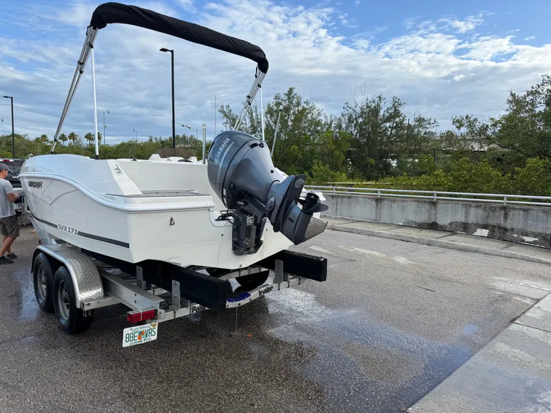 Slide: The Image of 2024 Starcraft SVX 171 OB boat on trailer, parked on wet pavement under cloudy sky. - 4