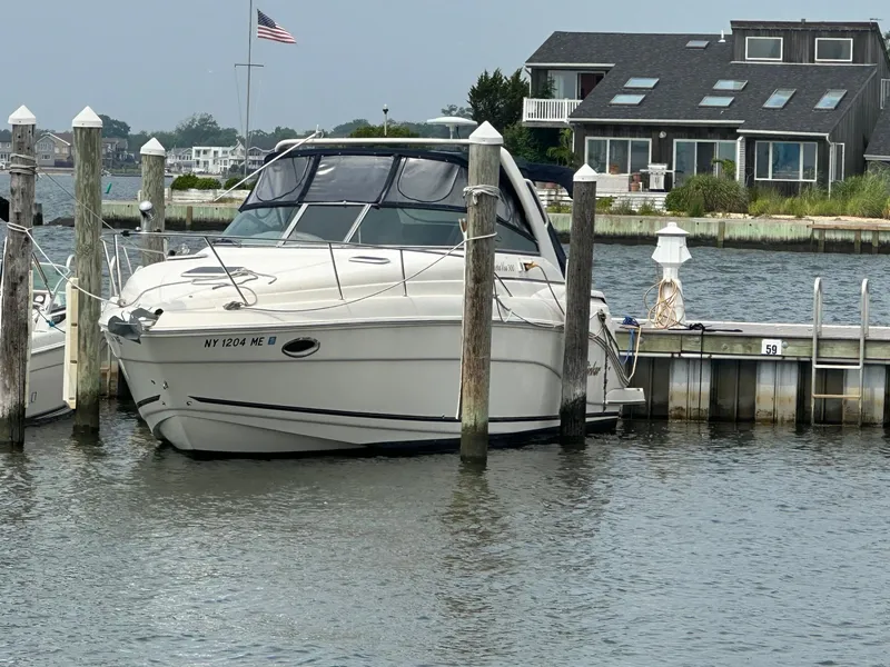 Slide: The Image of 2005 Rinker Fiesta Vee 300 docked at marina with waterfront house in background. - 2