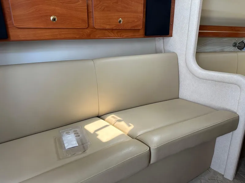 Slide: The Image of 2005 Rinker Fiesta Vee 300 interior with beige leather seating and wooden cabinets. - 8