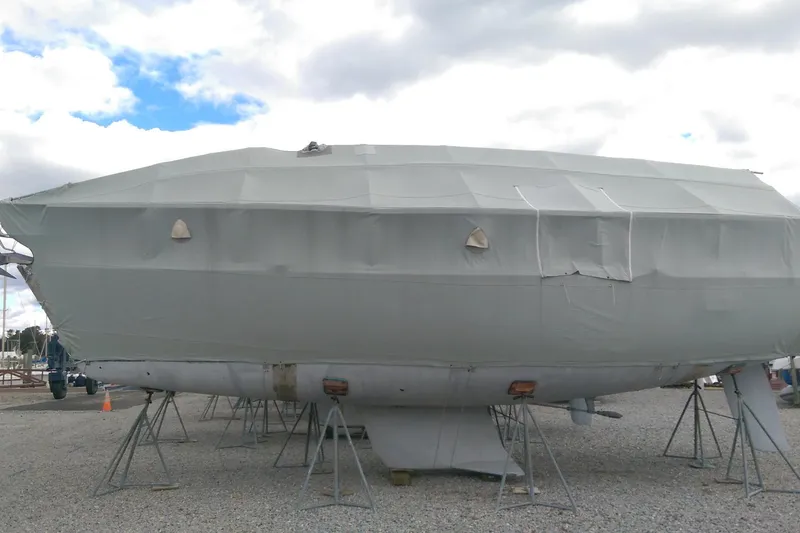 Slide: The Image of Covered 1998 Freedom 35 sailboat on stands under cloudy sky. - 19