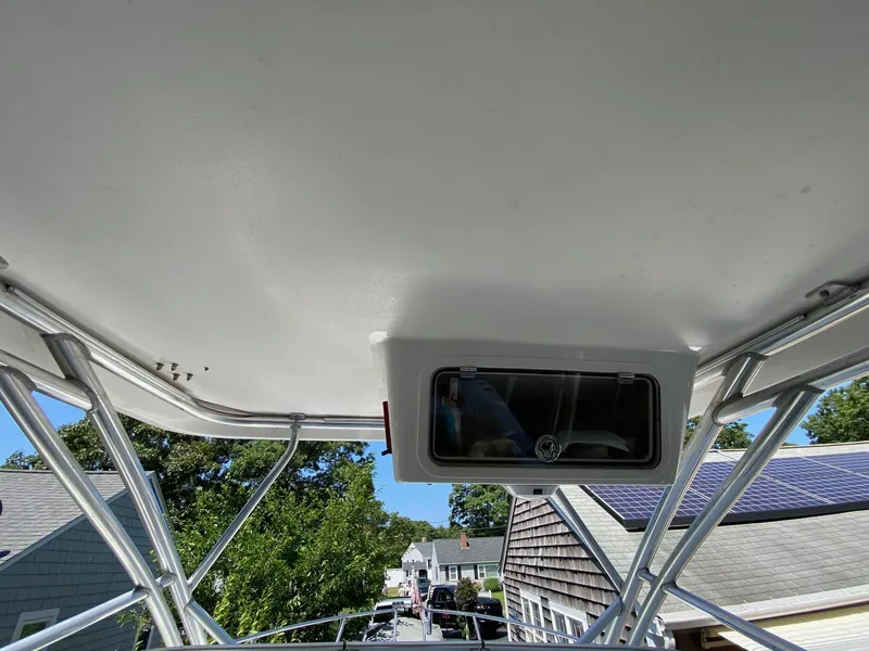 Slide: The Image of 2006 Century 2600 Walkaround boat cockpit with T-top and steering wheel, under clear blue sky. - 10