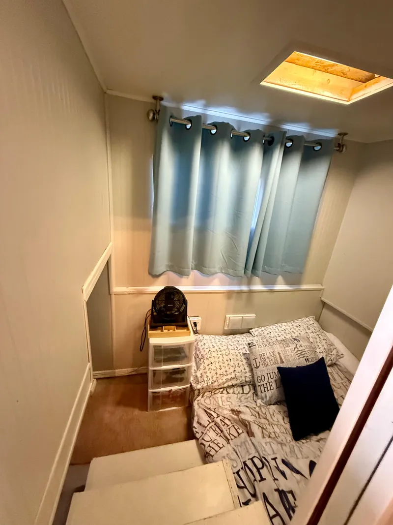 Slide: The Image of Cozy bedroom in a 1996 Jamestowner houseboat with blue curtains and a skylight. - 12