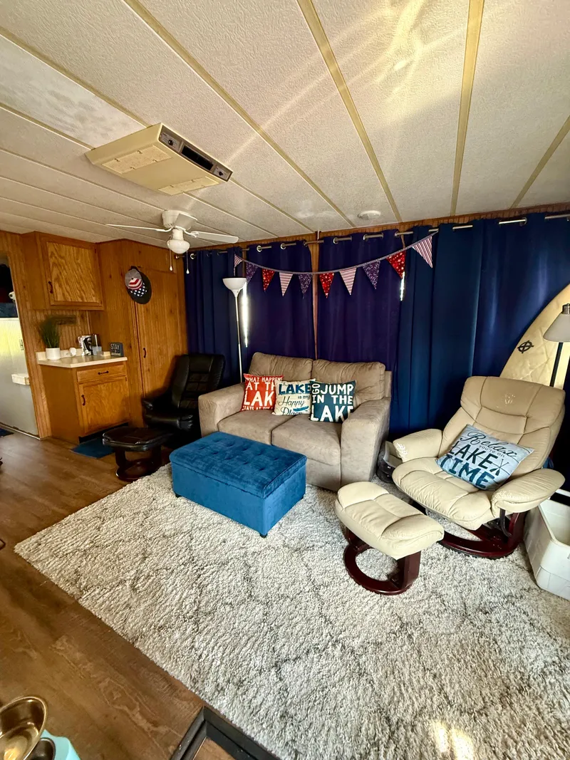 Slide: The Image of Cozy 1996 Jamestowner houseboat interior with plush seating, blue curtains, and decorative pillows. - 6