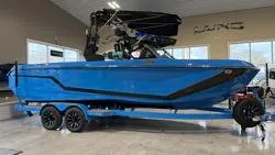 The Image of 2025 Nautique GS 24 boat in showroom, vibrant blue color, on a trailer. - 0