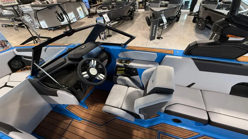 Slide: The Image of 2025 Nautique GS 24 boat interior with modern seating and steering wheel, displayed in showroom. - 2