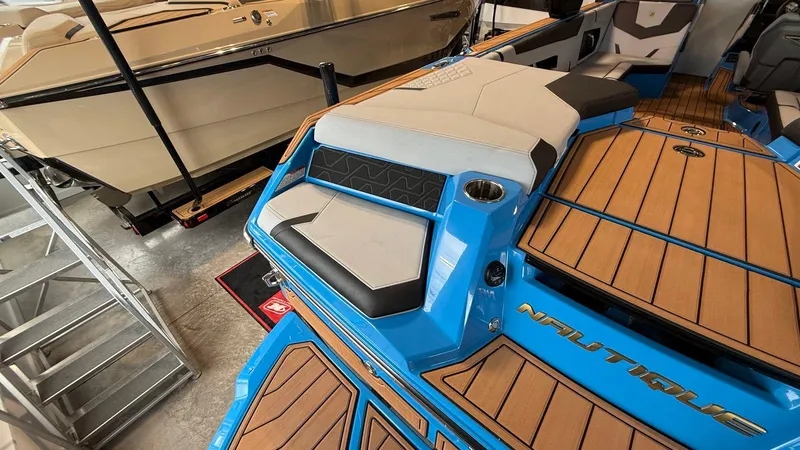Slide: The Image of 2025 Nautique GS 24 boat with blue accents and teak flooring in a showroom. - 4