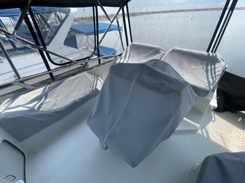 Slide: The Image of 1994 Carver 380 Santego SE boat interior with covered seating and helm, docked by the water. - 15