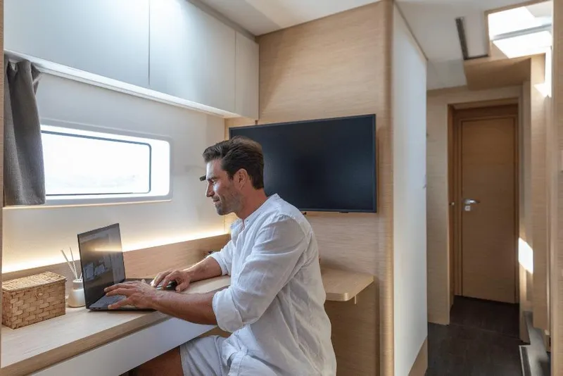 Slide: The Image of Man working on laptop inside 2026 Fountaine Pajot 44 yacht cabin. - 35