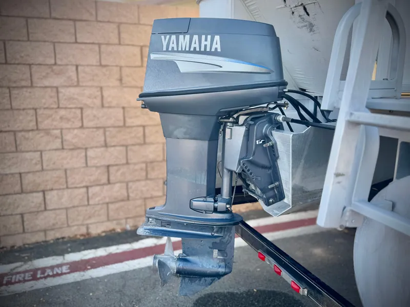 Slide: The Image of Outboard motor on a 2006 Godfrey Tuscany 2080 boat, parked near a brick wall. - 7