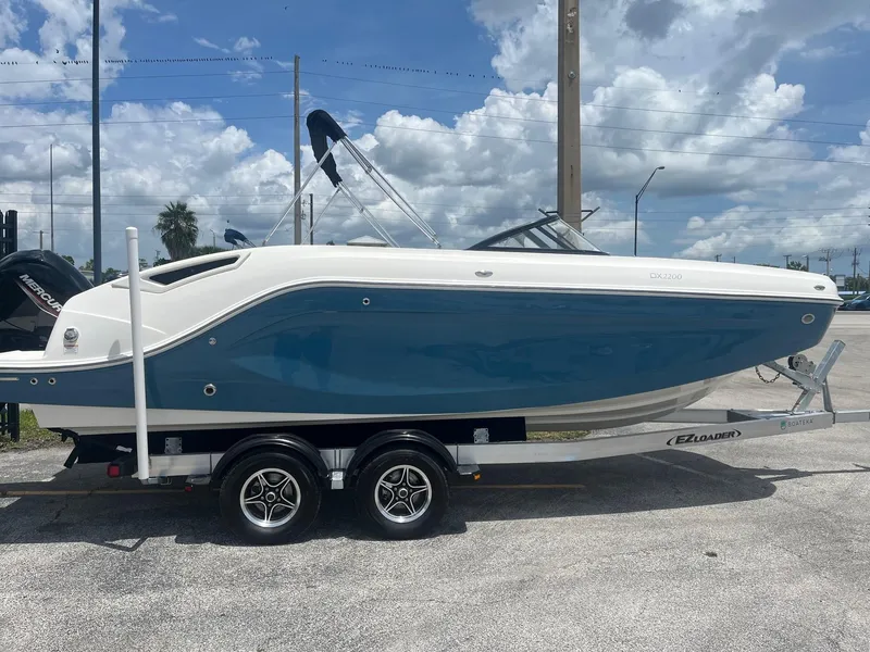 The Image of 2022 Bayliner DX 2200 boat on trailer under a clear blue sky. - 0