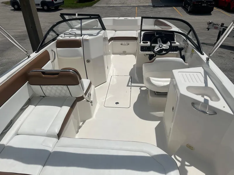 Slide: The Image of 2022 Bayliner DX 2200 boat interior with white and brown seating, steering wheel, and console. - 12