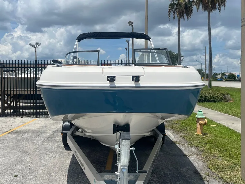 Slide: The Image of 2022 Bayliner DX 2200 boat on trailer, parked outdoors under cloudy sky. - 2