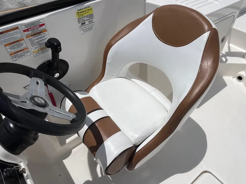 Slide: The Image of Captain's seat and steering wheel of 2022 Bayliner DX 2200 boat, featuring brown and white upholstery. - 8