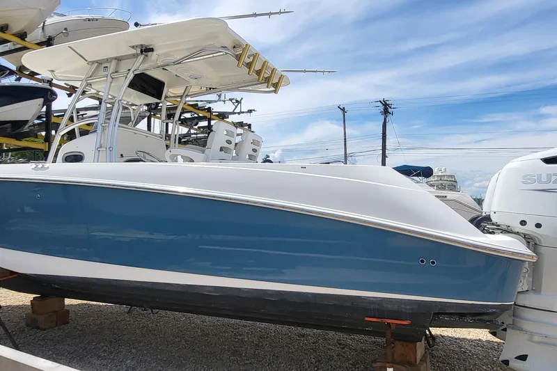 Slide: The Image of 2004 Boston Whaler 320 Outrage boat with blue hull, docked outdoors under clear sky. - 2