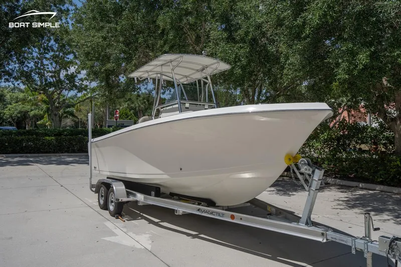 Slide: The Image of 2023 Sailfish 220 CC boat on trailer, parked outdoors under trees. - 4