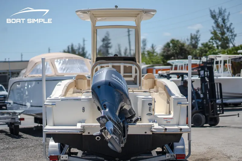 Slide: The Image of 2023 Scout 215 XSF boat with outboard motor on trailer, parked outdoors. - 4