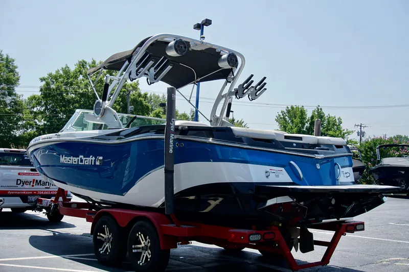 Slide: The Image of 2018 MasterCraft XT22 boat on trailer, blue and white design, parked outdoors. - 5