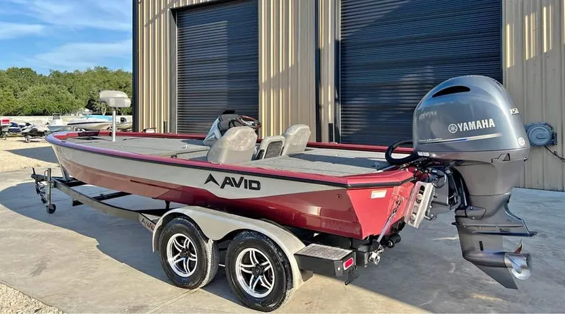 Slide: The Image of 2024 Avid 20 XB boat with Yamaha motor, parked on a trailer outside a building. - 4