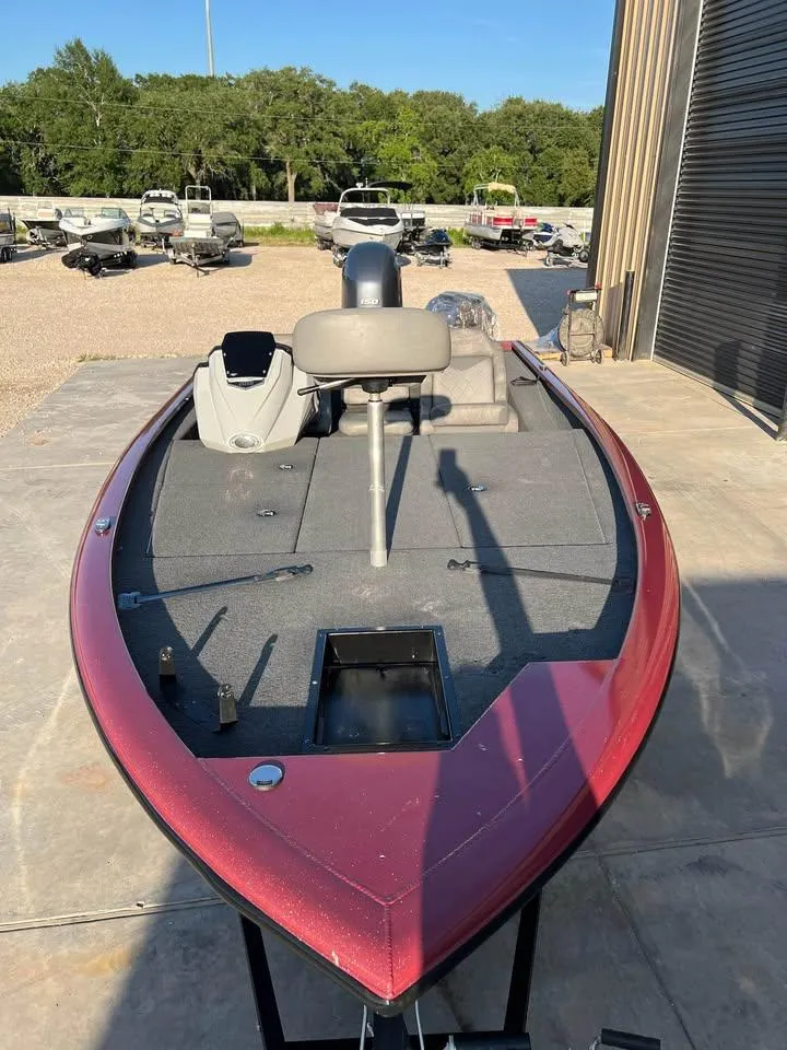 Slide: The Image of 2024 Avid 20 XB boat with red exterior, parked outdoors near other boats. - 6