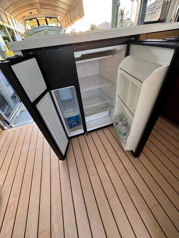 Slide: The Image of Open mini fridge on 2014 Cruisers Yachts 45 Cantius Black Diamond, showing interior shelves and bottled water. - 38