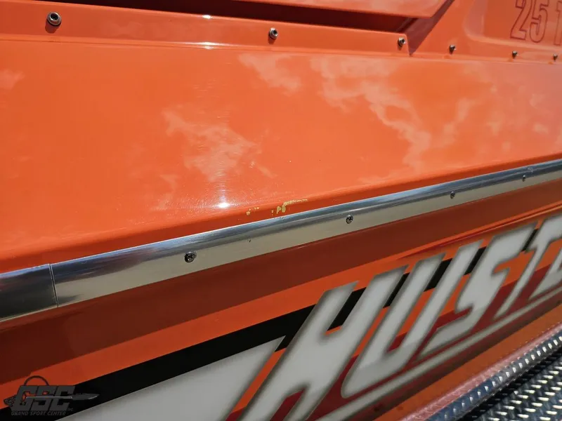 Slide: The Image of Orange 2019 Hustler 25 Talon Cat boat with visible branding and metal trim. - 13