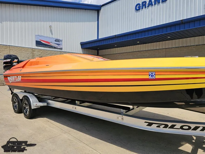 Slide: The Image of 2019 Hustler 25 Talon Cat boat with vibrant orange and yellow design on a trailer. - 17