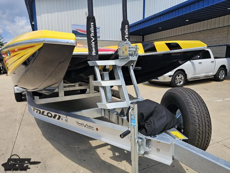 Slide: The Image of 2019 Hustler 25 Talon Cat boat on trailer, yellow and black design, parked outdoors. - 19