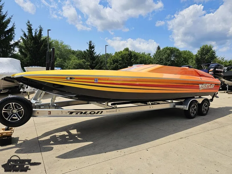Slide: The Image of 2019 Hustler 25 Talon Cat boat on trailer, vibrant orange and yellow design, parked outdoors. - 26