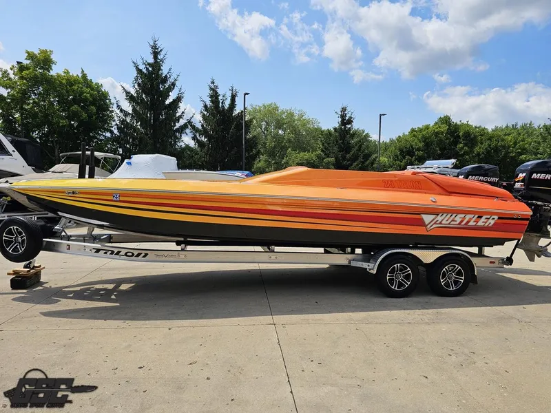 Slide: The Image of 2019 Hustler 25 Talon Cat boat with vibrant orange and yellow design on a trailer. - 28