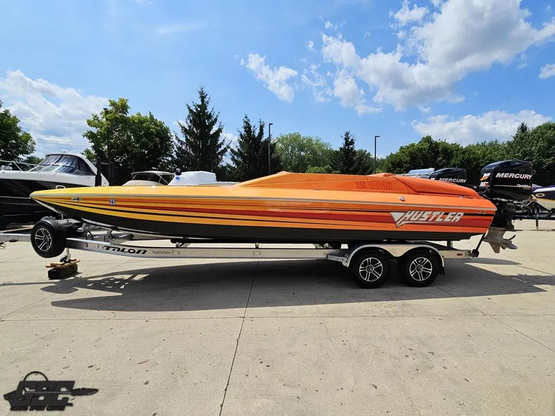 Slide: The Image of 2019 Hustler 25 Talon Cat boat on trailer, vibrant orange design, parked outdoors. - 29