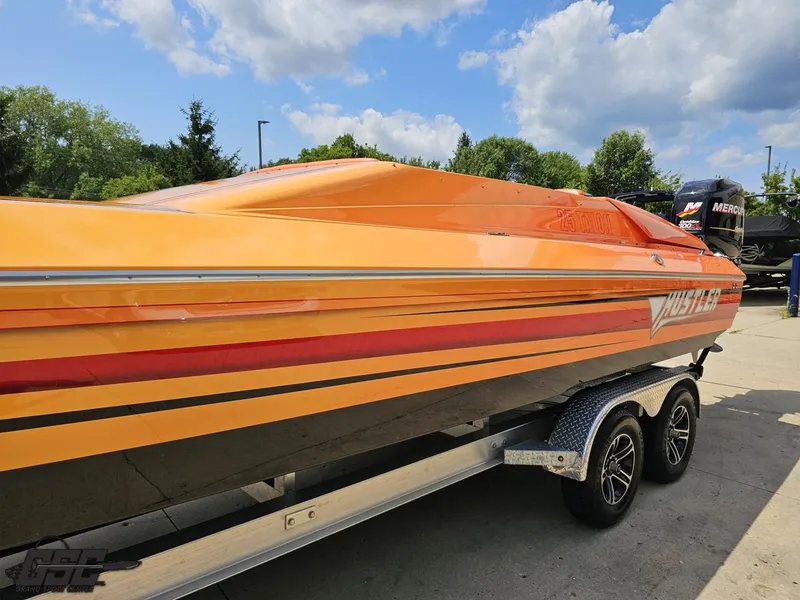 Slide: The Image of 2019 Hustler 25 Talon Cat boat on trailer, vibrant orange with red stripes, outdoors. - 31