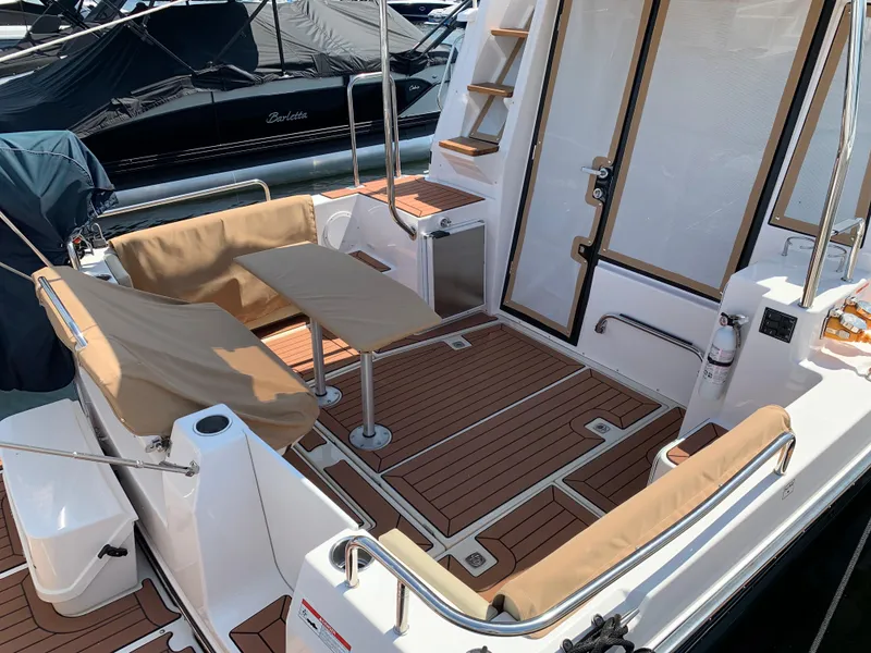 Slide: The Image of 2024 Ranger Tugs R-29 CB boat deck with seating and table, featuring wood-style flooring. - 10