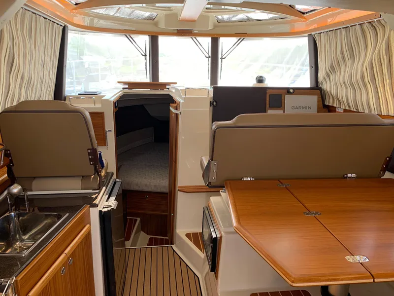 Slide: The Image of 2024 Ranger Tugs R-29 CB interior with wood finishes, seating, and navigation equipment. - 12