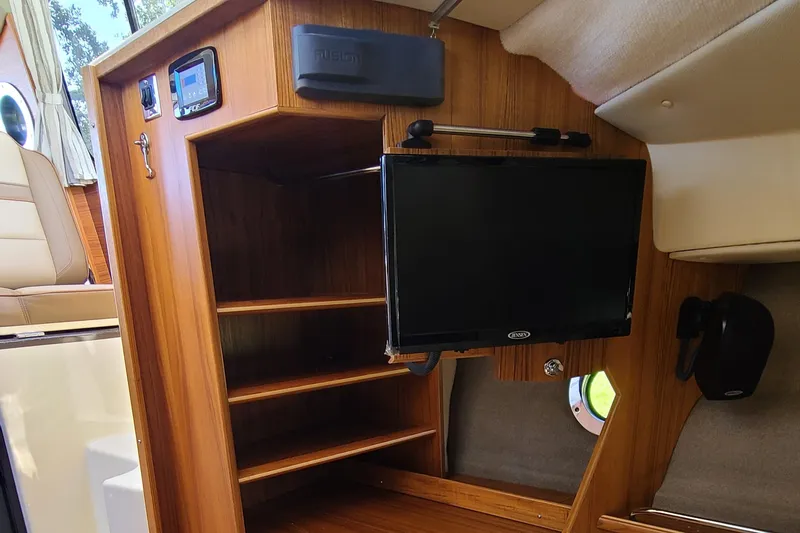 Slide: The Image of 2024 Ranger Tugs R-29 CB interior with wooden shelves and mounted TV. - 21
