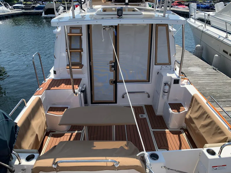 Slide: The Image of 2024 Ranger Tugs R-29 CB boat deck with seating and wood accents at a marina. - 8